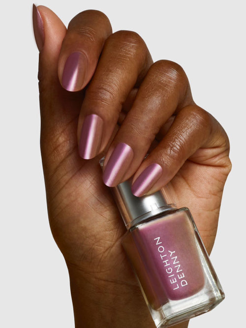 Naughty List limited edition nail colour on nails holding bottle - a rose gold metallic with a hint of plum.